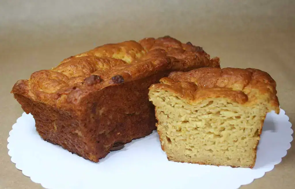 Ein Laib Brot mit einer abgeschnittenen Scheibe, perfekt zum backwaren online bestellen, auf einem weißen Teller.